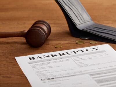 bankruptcy form with wooden gavel, coins and wallet on brown wooden table