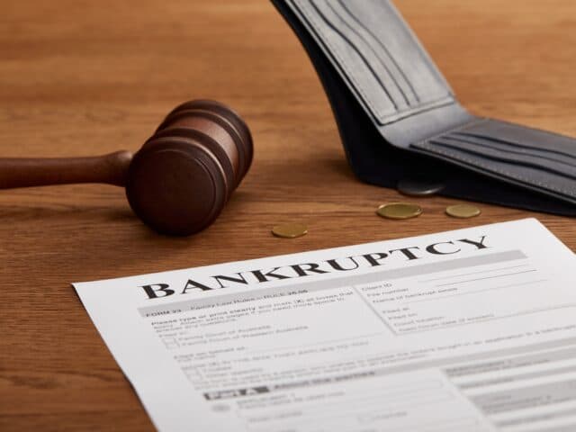 bankruptcy form with wooden gavel, coins and wallet on brown wooden table
